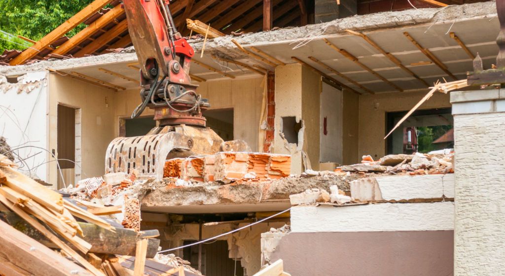 Excavator performing building demolition and site cleanup on a residential structure in Northeast Texas