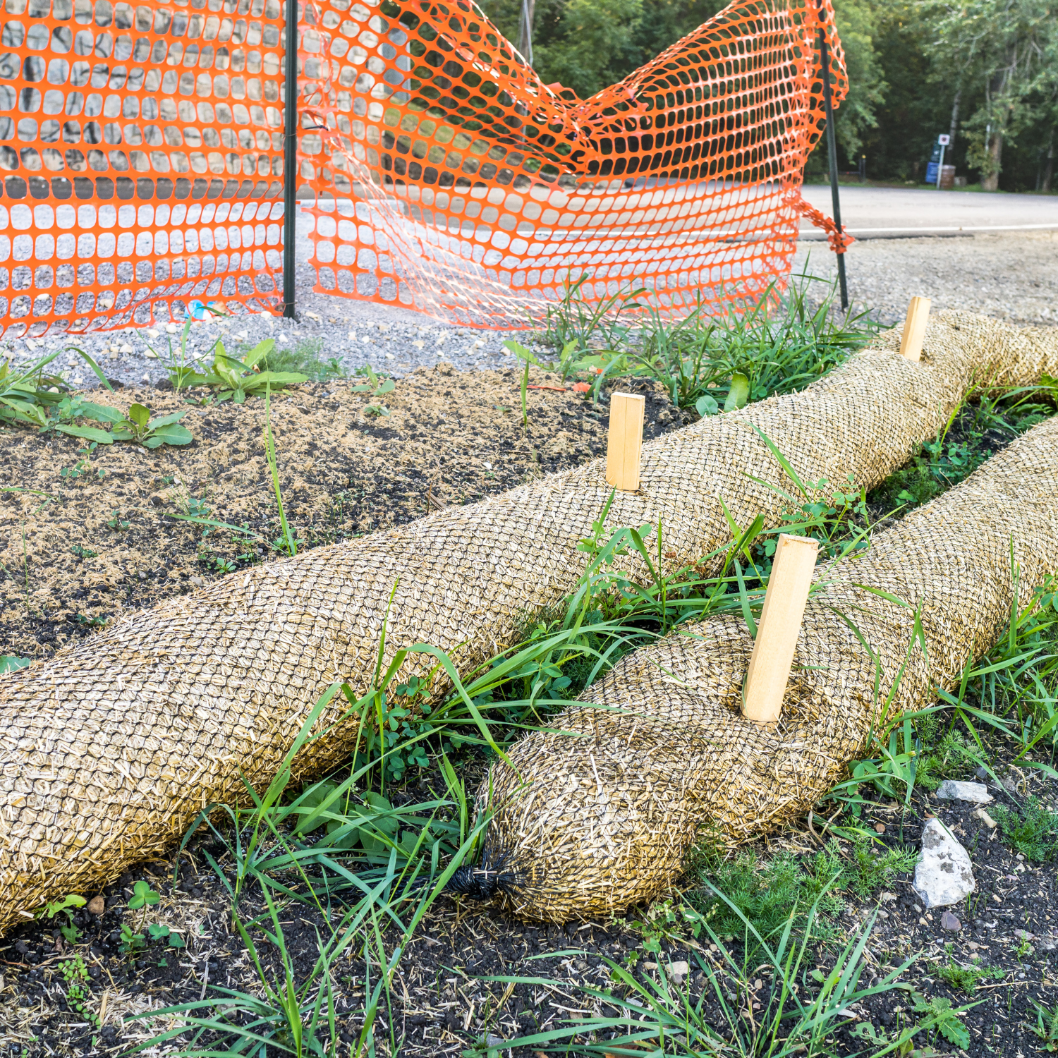 Erosion control wattles installed along a construction site perimeter with orange safety fencing – Outta Bounds Excavation implementing best practices for sediment and stormwater management.